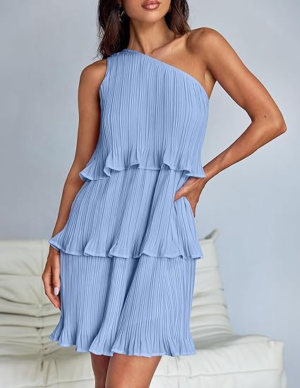 Woman wearing a light blue one-shoulder dress with ruffled layers on a neutral background